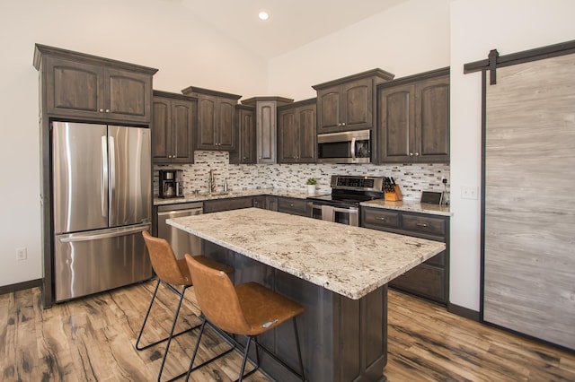 8259 Barton Ave NW, Buffalo, MN 55313 - kitchen with appliances with stainless steel finishes, dark brown cabinetry, tasteful backsplash, a breakfast bar, and a kitchen island