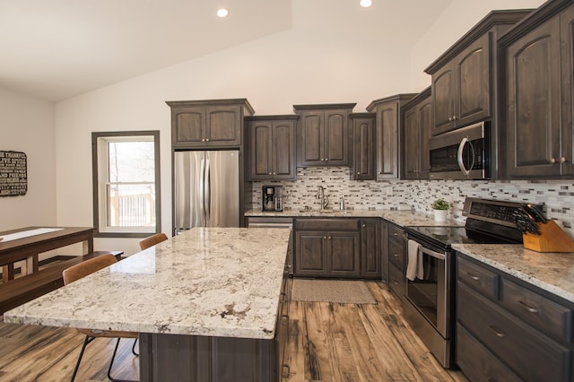 8259 Barton Ave NW, Buffalo, MN 55313 - kitchen with appliances with stainless steel finishes, lofted ceiling, backsplash, light wood-type flooring, and light stone counters