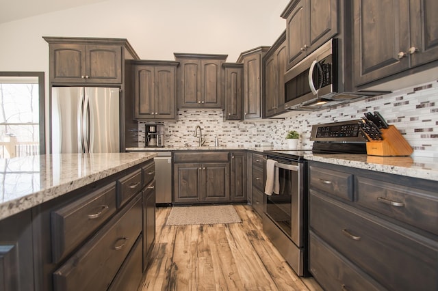 8259 Barton Ave NW, Buffalo, MN 55313 - kitchen featuring stainless steel appliances, light wood-style floors, tasteful backsplash, dark brown cabinets, and light stone countertops