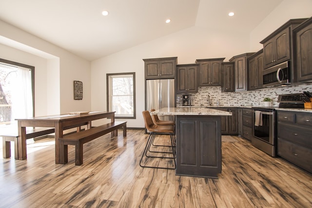 8259 Barton Ave NW, Buffalo, MN 55313 - kitchen with stainless steel appliances, lofted ceiling, plenty of natural light, dark brown cabinetry, and a kitchen island