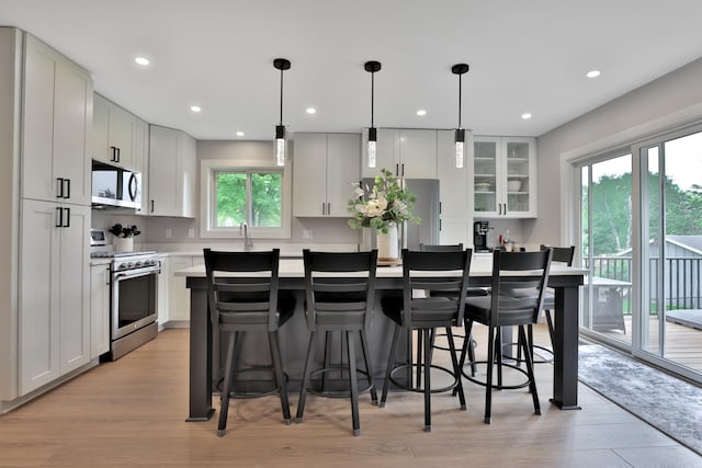 8466 Isleton Ct S, Cottage Grove, MN 55016 - kitchen with stainless steel appliances, a kitchen island, light wood-type flooring, a kitchen breakfast bar, and recessed lighting