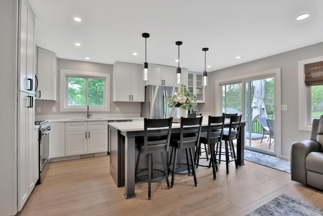 8466 Isleton Ct S, Cottage Grove, MN 55016 - kitchen with stainless steel appliances, a sink, a kitchen bar, light countertops, and healthy amount of natural light