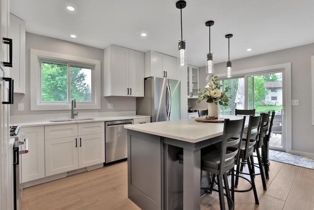 8466 Isleton Ct S, Cottage Grove, MN 55016 - kitchen with stainless steel appliances, a sink, a breakfast bar area, light countertops, and light wood finished floors
