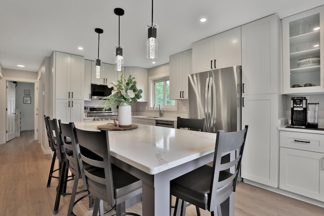 8466 Isleton Ct S, Cottage Grove, MN 55016 - kitchen featuring appliances with stainless steel finishes, a kitchen bar, glass insert cabinets, white cabinets, and recessed lighting