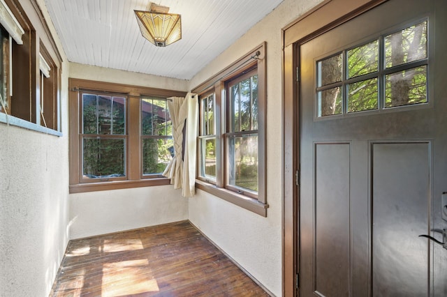 unfurnished sunroom featuring a textured wall, wood finished floors, and wood ceiling