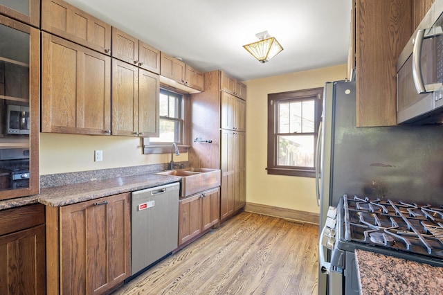 kitchen with appliances with stainless steel finishes, light wood-style floors, a sink, and plenty of natural light