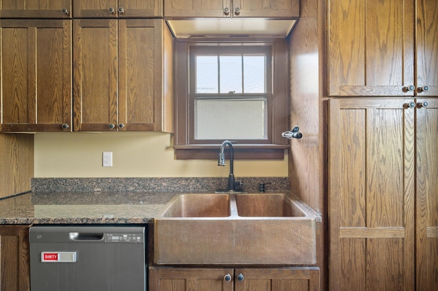 kitchen with dishwashing machine, a sink, and dark stone counters