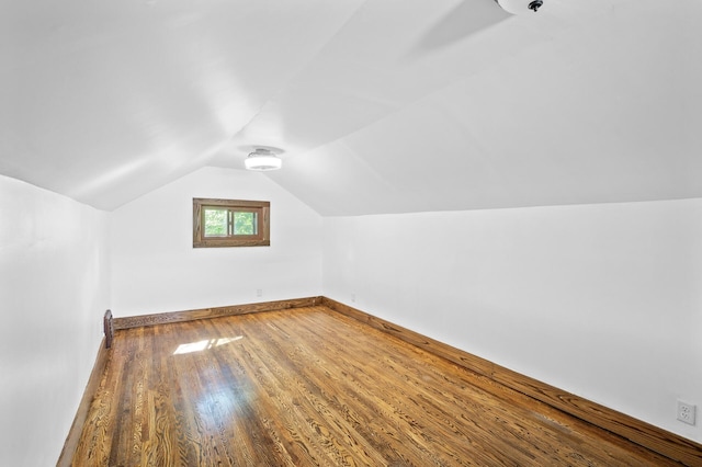additional living space with wood finished floors, lofted ceiling, and baseboards