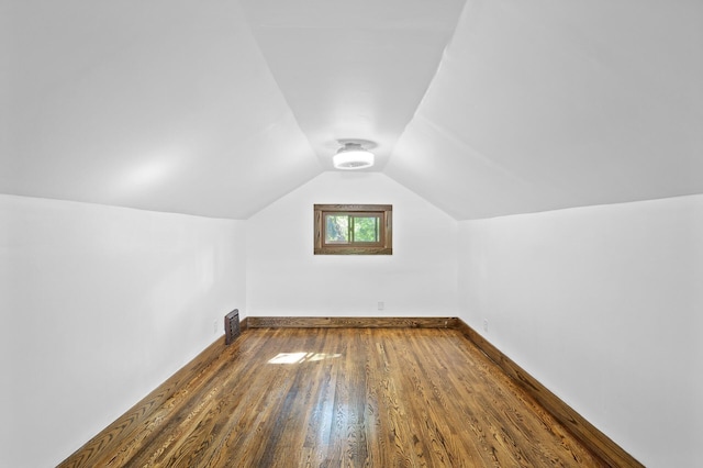 additional living space with dark wood-type flooring, lofted ceiling, and baseboards