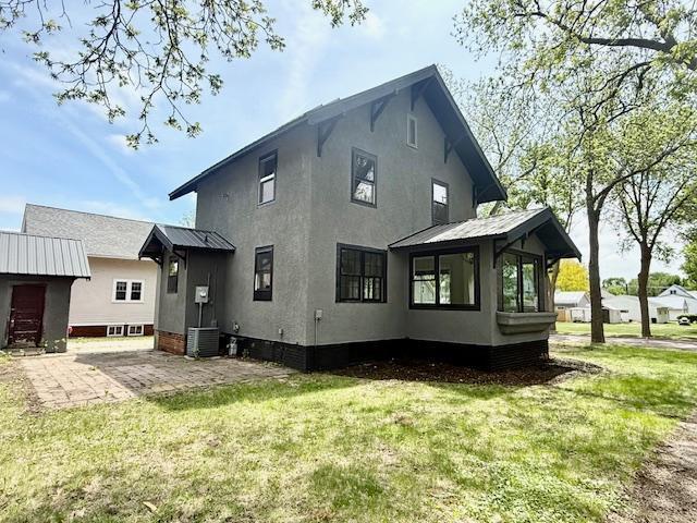 503 3rd St, Redwood Falls, MN 56283 - back of property featuring a lawn, stucco siding, and central AC unit