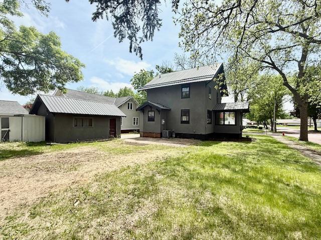 503 3rd St, Redwood Falls, MN 56283 - back of property featuring metal roof, a yard, and stucco siding