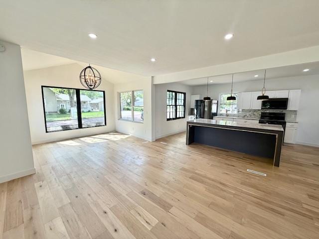 503 3rd St, Redwood Falls, MN 56283 - unfurnished living room with light wood-style floors, a chandelier, baseboards, recessed lighting, and vaulted ceiling