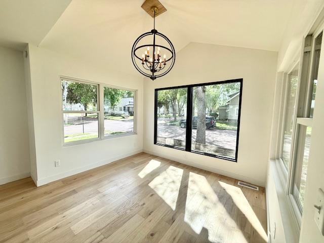 503 3rd St, Redwood Falls, MN 56283 - unfurnished dining area with a chandelier, lofted ceiling, light wood finished floors, and baseboards