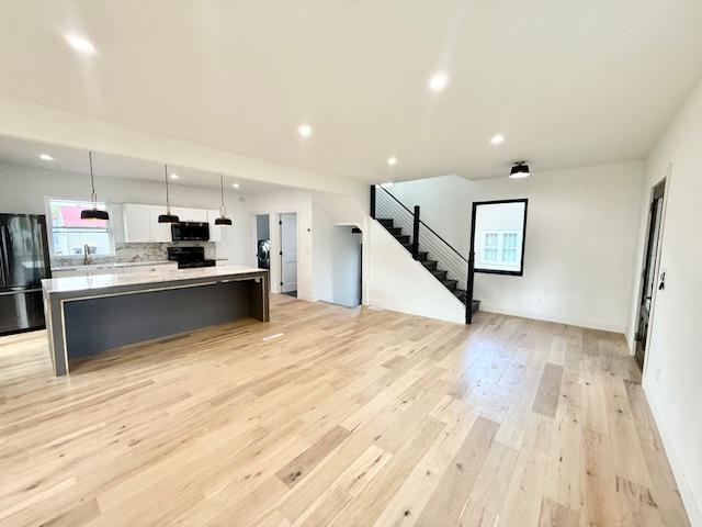 503 3rd St, Redwood Falls, MN 56283 - kitchen featuring black appliances, light countertops, white cabinetry, a spacious island, and light wood-style floors