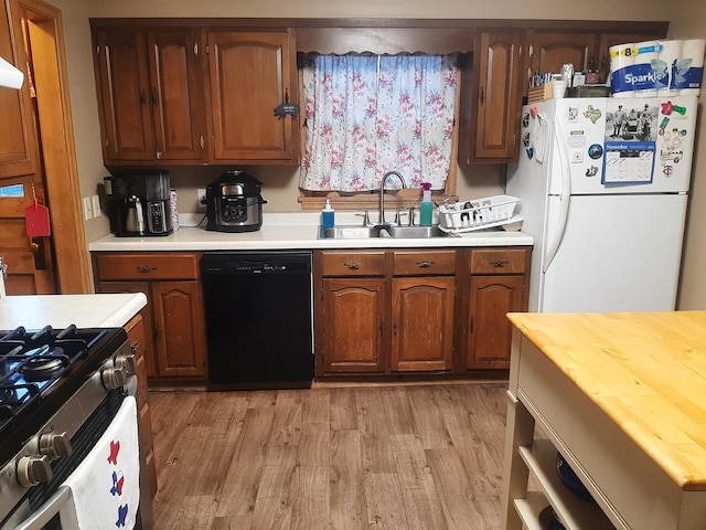 207 7th Ave S, Saint James, MN 56081 - kitchen featuring dishwasher, freestanding refrigerator, a sink, stainless steel gas stove, and light wood-style flooring