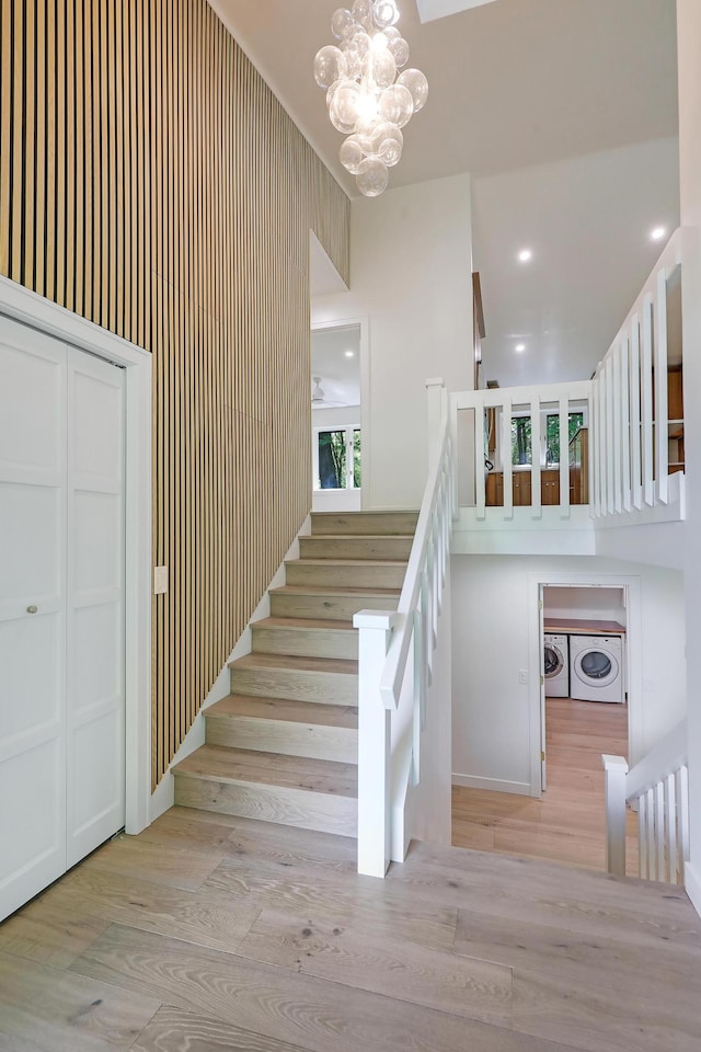745 Virginia Shores Cir, Victoria, MN 55331 - staircase featuring a chandelier, wood finished floors, washer and clothes dryer, and a high ceiling