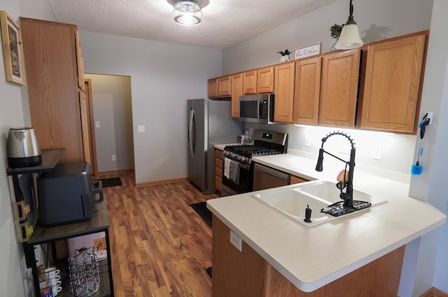 9467 Golden Eagle Ln, Monticello, MN 55362 - kitchen featuring stainless steel appliances, a sink, wood finished floors, a peninsula, and light countertops