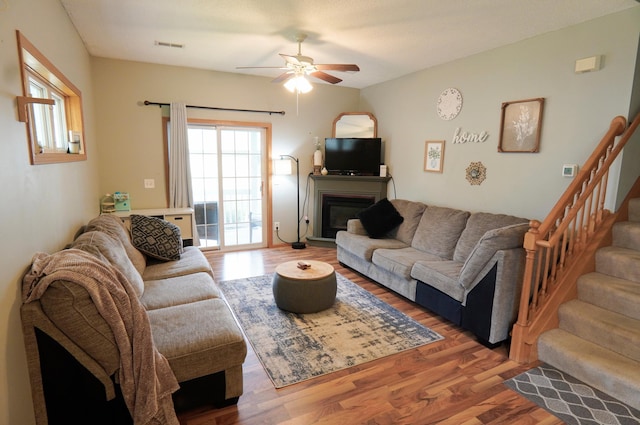 9467 Golden Eagle Ln, Monticello, MN 55362 - living room with ceiling fan, wood finished floors, a glass covered fireplace, and stairway