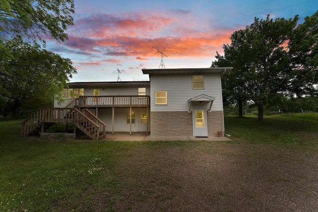 1231 135th St, Amery, WI 54005 - back of house at dusk featuring stairs, stone siding, a deck, a patio, and a yard