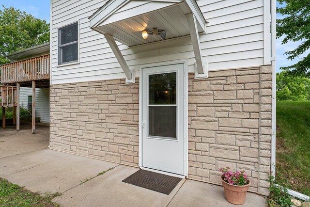 1231 135th St, Amery, WI 54005 - doorway to property featuring stone siding, a deck, and a patio