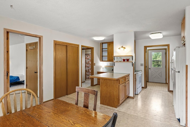 1231 135th St, Amery, WI 54005 - kitchen featuring white appliances, a peninsula, a kitchen bar, and brown cabinetry