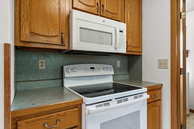 1231 135th St, Amery, WI 54005 - kitchen with white appliances, brown cabinetry, and tasteful backsplash