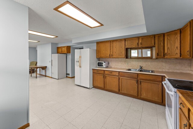 1231 135th St, Amery, WI 54005 - kitchen featuring white appliances, brown cabinets, tasteful backsplash, and a textured ceiling