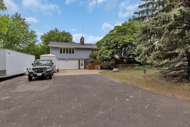 311 131st Ave NE, Spicer, MN 56288 - view of front facade with a chimney, a garage, driveway, and board and batten siding
