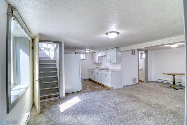 1010 University Dr N, Fargo, ND 58102 - kitchen with freestanding refrigerator, a sink, white cabinets, a textured ceiling, and light carpet