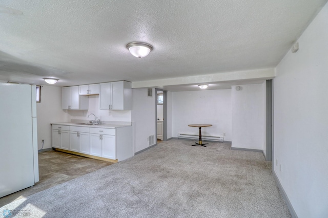 1010 University Dr N, Fargo, ND 58102 - kitchen featuring freestanding refrigerator, a sink, baseboard heating, a textured ceiling, and white cabinetry