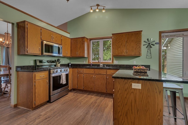 16474 63rd St SE, Becker, MN 55308 - kitchen with stainless steel appliances, brown cabinetry, light wood-style flooring, a breakfast bar, and high vaulted ceiling