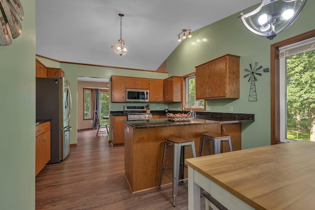 16474 63rd St SE, Becker, MN 55308 - kitchen with appliances with stainless steel finishes, brown cabinetry, lofted ceiling, a peninsula, and dark wood finished floors