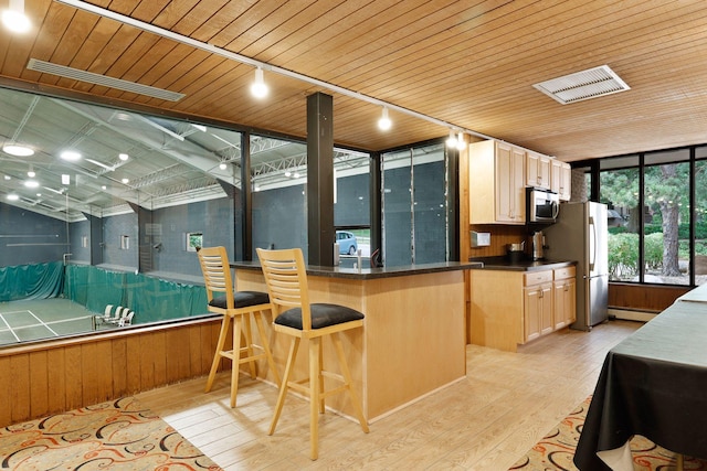 6085 Lincoln Dr Unit 123, Edina, MN 55436 - kitchen with appliances with stainless steel finishes, light wood-type flooring, dark countertops, light brown cabinetry, and a breakfast bar area