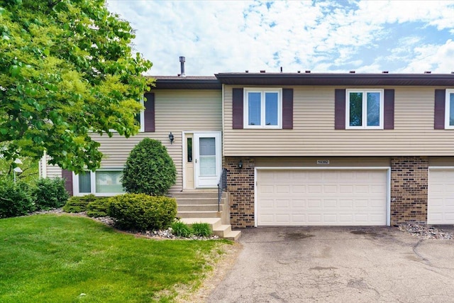 10382 Juniper Ln, Eden Prairie, MN 55347 - bi-level home with brick siding, an attached garage, asphalt driveway, and a front lawn