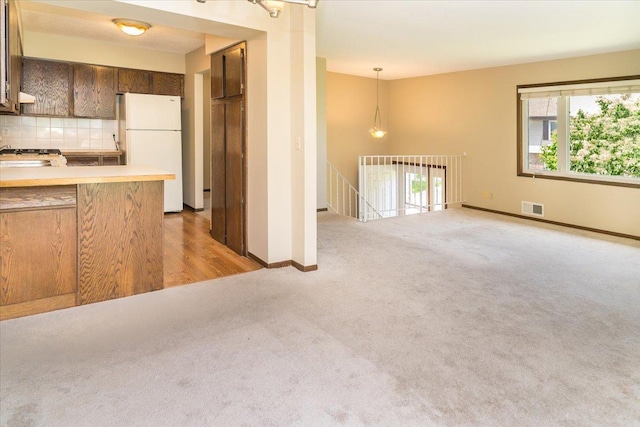10382 Juniper Ln, Eden Prairie, MN 55347 - kitchen with freestanding refrigerator, light carpet, backsplash, light countertops, and pendant lighting
