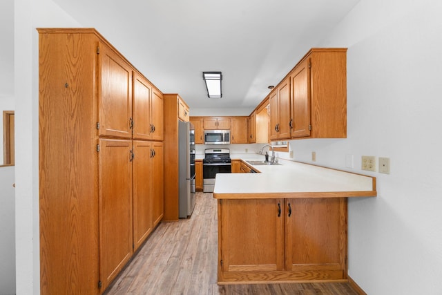 39094 Riverside Ct, North Branch, MN 55056 - kitchen with stainless steel appliances, a sink, a peninsula, and light wood-style floors