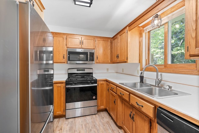 39094 Riverside Ct, North Branch, MN 55056 - kitchen with stainless steel appliances, a sink, light countertops, light wood-style flooring, and brown cabinets