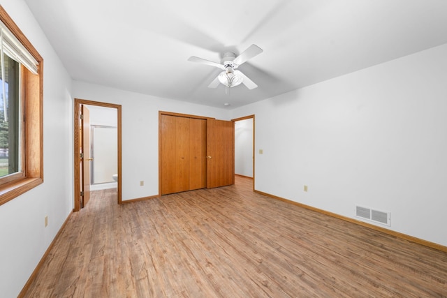 39094 Riverside Ct, North Branch, MN 55056 - unfurnished bedroom featuring light wood-style flooring, baseboards, a closet, ensuite bathroom, and ceiling fan