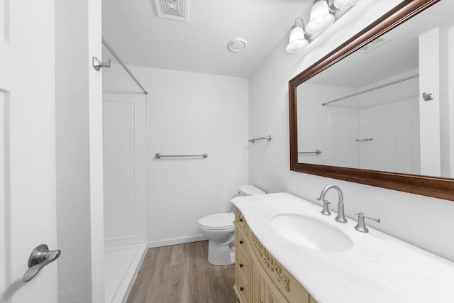 39094 Riverside Ct, North Branch, MN 55056 - bathroom with a shower, wood finished floors, toilet, vanity, and a textured ceiling