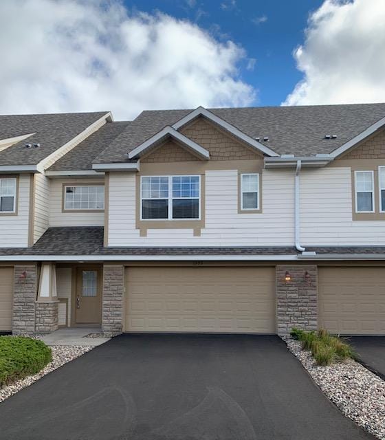 1595 Fox Hunt Way, Victoria, MN 55386 - view of property featuring a garage, stone siding, asphalt driveway, and a shingled roof