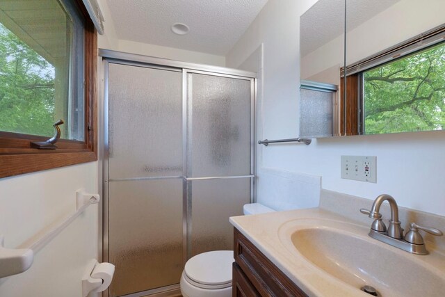 bathroom featuring a stall shower, toilet, vanity, and a textured ceiling
