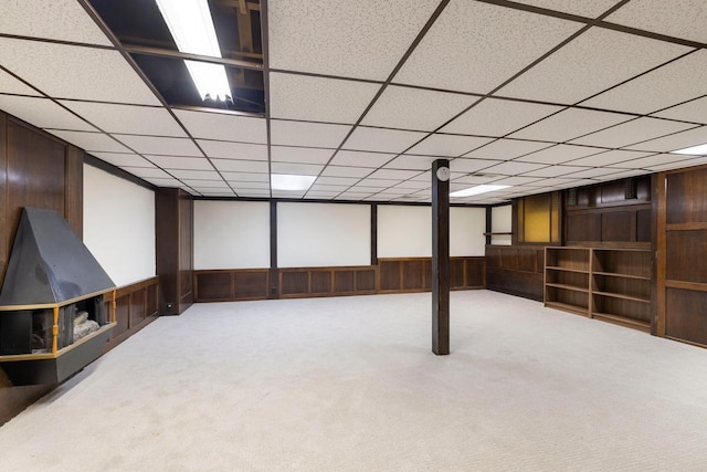 finished below grade area featuring carpet, wooden walls, and a drop ceiling