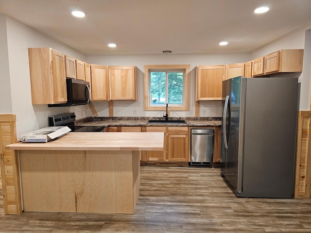 kitchen with appliances with stainless steel finishes, a sink, light brown cabinetry, a peninsula, and dark wood-style floors