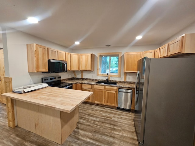 kitchen featuring stainless steel appliances, a sink, light brown cabinets, a peninsula, and butcher block counters