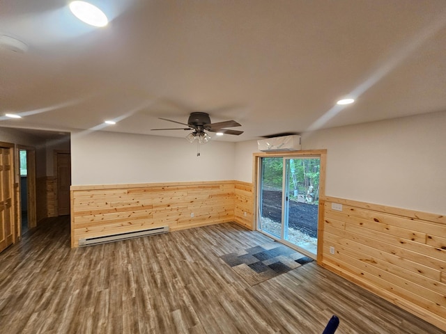 spare room with baseboard heating, a wall mounted AC, wood finished floors, a wainscoted wall, and wood walls