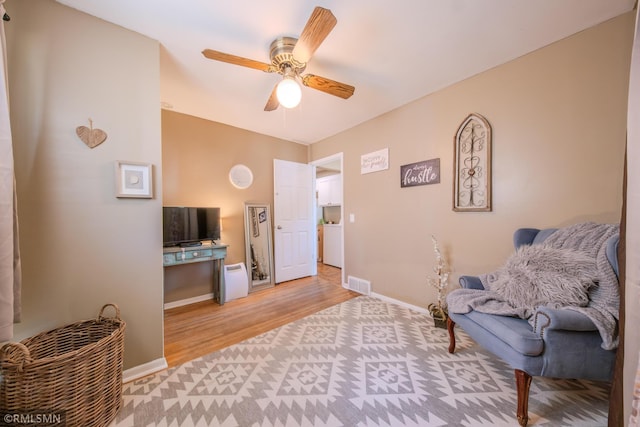 living area featuring a ceiling fan, light wood-type flooring, baseboards, a desk, and washer / clothes dryer