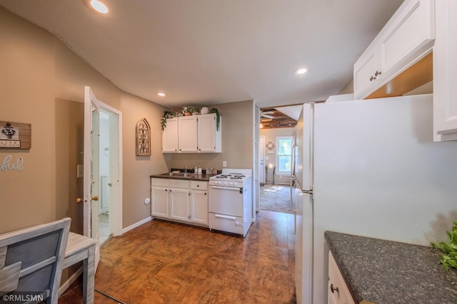 kitchen featuring white appliances, white cabinets, recessed lighting, dark stone countertops, and baseboards