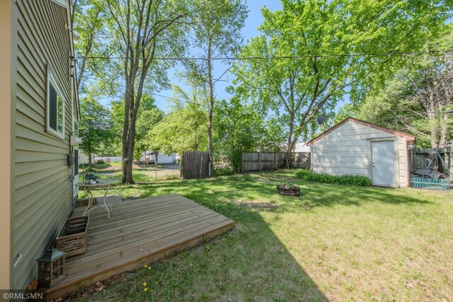 view of yard featuring an outdoor fire pit, a deck, a storage unit, and an outbuilding