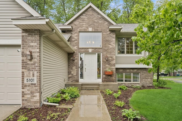 5101 201st St N, Forest Lake, MN 55025 - doorway to property with brick siding, an attached garage, a shingled roof, and a yard