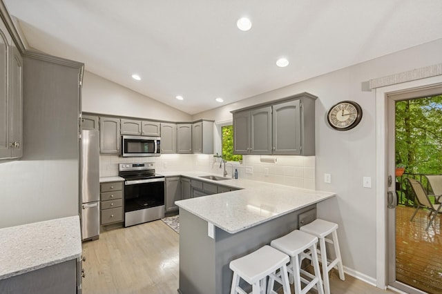 5101 201st St N, Forest Lake, MN 55025 - kitchen featuring appliances with stainless steel finishes, gray cabinets, a peninsula, a sink, and lofted ceiling
